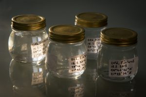 Glass jars filled with sea water. Water has been collected from Utö Finland at 18th of February 2018 on shore south from the lighthouse.